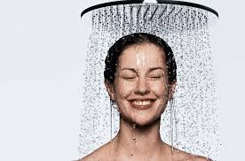 Woman smiling under rain shower head